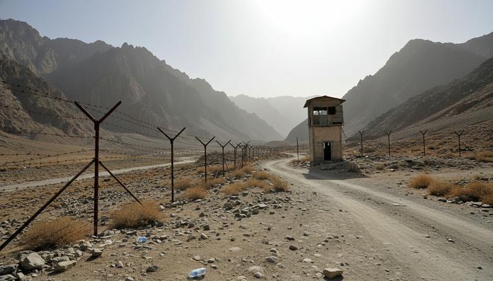 Пустынный пограничный переход в скалистых горах между Пакистаном и Афганистаном с колючей проволокой и сторожевой вышкой.