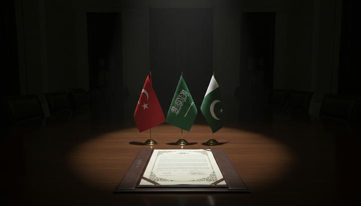 На столе в переговорной комнате стоят флаги Турции, Саудовской Аравии и Пакистана рядом с текстом договора.