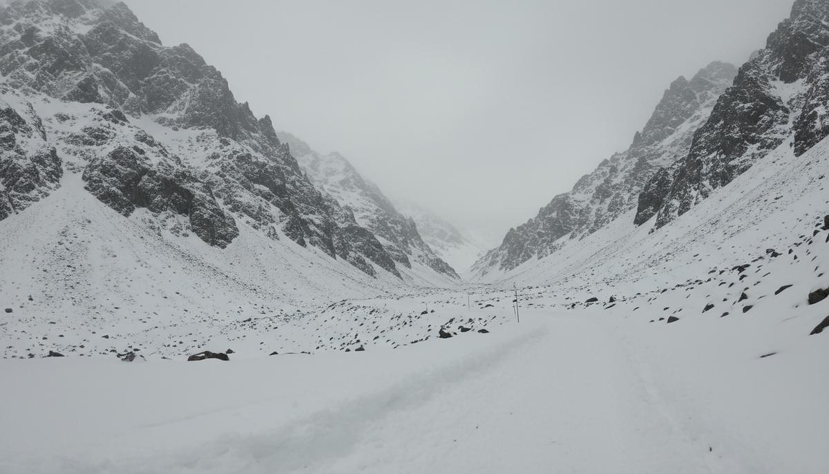 Заснеженный горный перевал в долине Тирах в Пакистане. Дорога заблокирована глубокими сугробами, вокруг суровые скалистые горы.